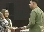 Dian Muhtadiah Hamna, M.Si. menyerahkan ijazah doktor kepada suaminya, Muhammad Awais. (Foto:MDA).